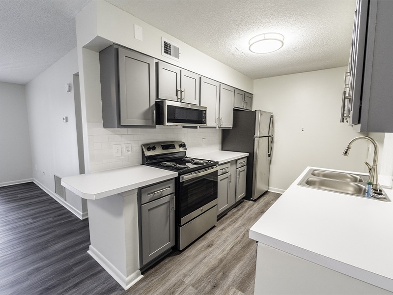 A kitchen with a white counter top and stainless steel appliances.
